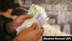 A man counts his banknotes and traveler's checks in Tehran, August 21, 2019