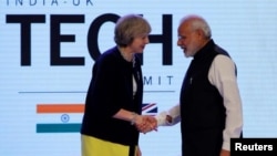 Britain's Prime Minister Theresa May shakes hands with her Indian counterpart Narendra Modi during the India-UK Tech Summit in New Delhi on November 7.