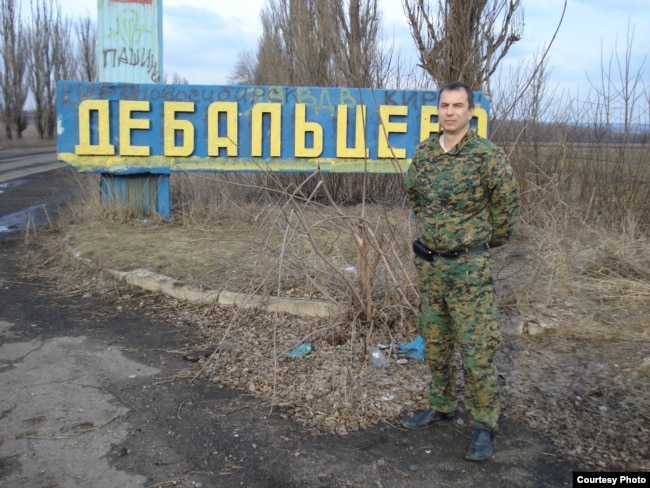 Казак Евгений Панчук у стенда названием украинского города Дебальцево, на котором можно увидеть надписи "Новосибирск", "ВДВ".