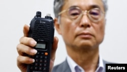 Directorul firmei japoneze Icom Inc, Yoshiki Enomoto, arată modelul de walkie-talkie IC-V82 la Osaka pe 19 septembrie, spunând că nu se mai produce din 2014.