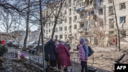 Local residents stand outside damaged buildings at the site of an air attack in Slovyansk in eastern Ukraine on March 10. 
