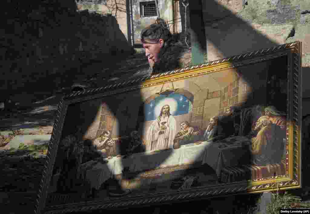 A woman carries a Christian painting out of her home before fleeing Karvachar/Kalbacar.