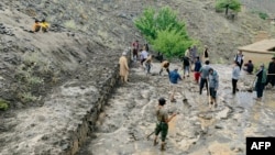 Afghan villagers shovel mud on July 15 following flash floods after heavy rainfall in the Dara district of Panjshir Province. 