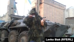 At Slovyansk's animal-feed factory, where a Ukrainian National Guard unit is stationed, one of the men poses dressed in a camouflage cloak he's just been delivered, holding a sausage and a bag of oranges. 