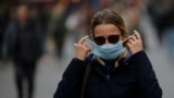 A woman adjusts her protective face mask as she walks along a street amid the outbreak of the coronavirus disease (COVID-19) in Kyiv.