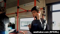 Мальчик с телефонов в салоне автобуса в Туркменистане.