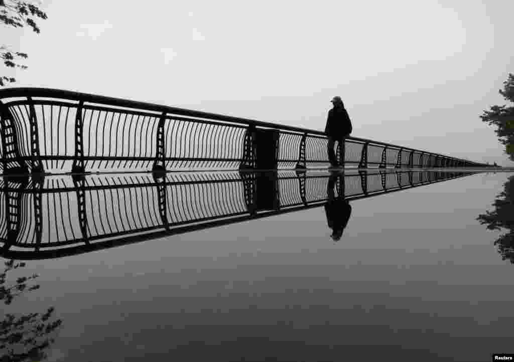 Fog shrouds the skyline of New York as a woman walks through a park along the Hudson River in Hoboken, New Jersey. (Reuters/Gary Hershorn)