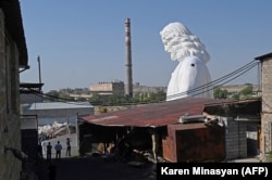 People photograph the top section of the Jesus statue at an open-air workshop in Zovuni, near Yerevan, where artist Armen Samvelian built the monument.