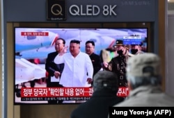 Oamenii urmăresc o emisiune de știri de televiziune care prezintă imagini cu liderul nord-coreean Kim Jong-un.