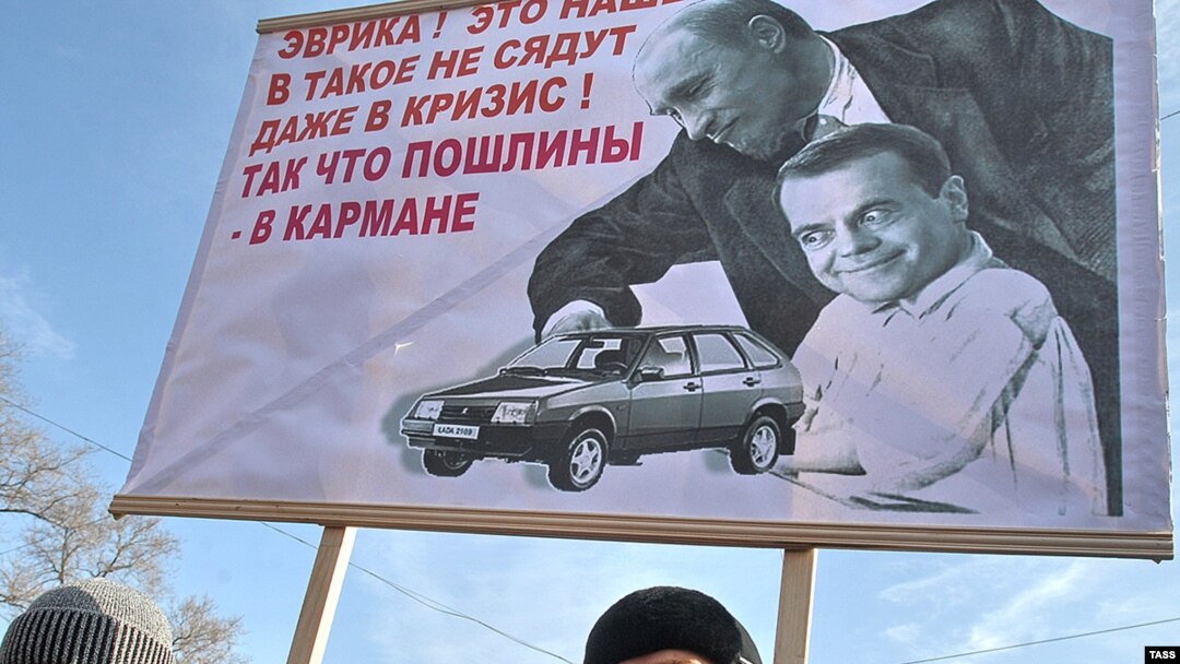 Россия, Владивосток. Митингующие держат растяжку с карикатурой на Владимира Путина и Дмитрия Медведева, февраль 2009