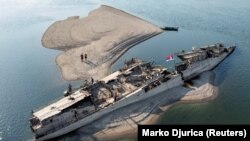 People explore the wreckage of a German warship near Prahovo, Serbia, on August 13.<br><br>The ship is one of several World War II relics being uncovered by historically low water levels on the Danube River amid an ongoing drought.