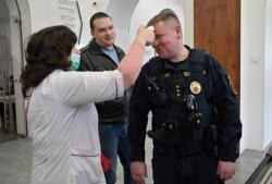 A medical worker checks the temperature of a security guard at Kyiv City Hall on March 13.