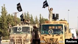 Militant Islamist fighters wave flags as they take part in a military parade in Syria's northern Raqqa province on June 30 to celebrate the announcement of a new Islamic Caliphate by ISIL. 