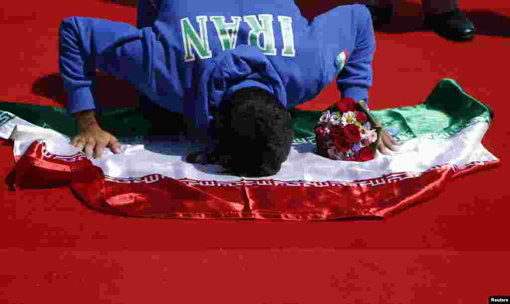 Iranian Gold medalist Mohsen Shadi Naghadeh kneels to touch the Iranian national flag during a medal ceremony in Incheon, South Korea, for the men&#39;s single sculls race of the rowing competition during the 17th Asian Games. (Reuters/Kim Hong-Ji) 