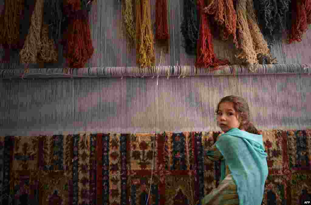 A young Afghan refugee girl weaves a carpet at a small factory in Peshawar, Pakistan. Hundreds of thousands of people have fled Afghanistan during the last three decades of war, with a majority of them taking refuge in neighboring Pakistan. (AFP/A. Majeed)