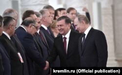 Mirziyoev (center) meets with Usmanov in the presence of Russian President Vladimir Putin (right).