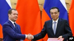 Russian Prime Minister Dmitry Medvedev, left, and Chinese Premier Li Keqiang, right, attend a signing ceremony at the Great Hall of the People in Beijing Wednesday, Nov. 7, 2018. (Thomas Peter/Pool Photo via AP)