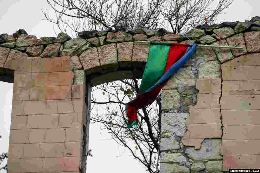 An Azerbaijan flag is draped over the ruins of a destroyed military recruitment office in the recaptured city of Fuzuli on November 18.