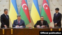Президент України Петро Порошенко (ліворуч) та президент Азербайджану Ільгам Алієв підписують документи у Баку. 14 липня 2016 року