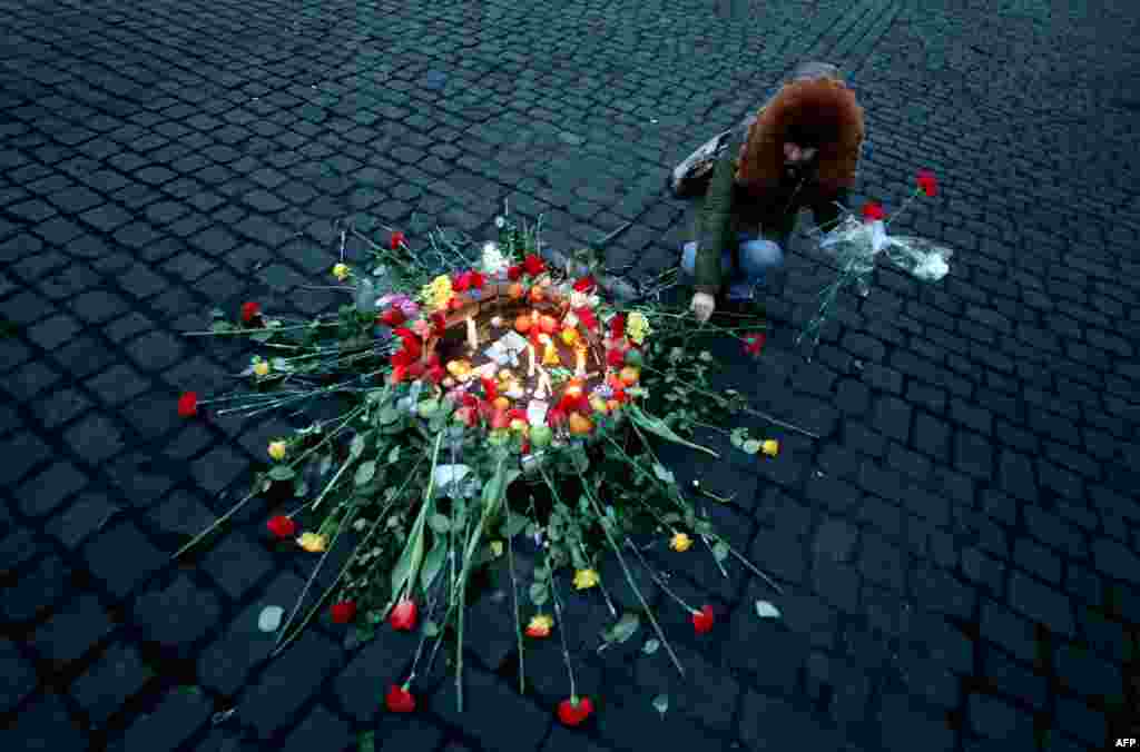 A woman places a flower on February 21 near the site in central Kyiv where an antigovernment protester was killed during clashes with police the previous evening. (AFP/Sergey Gapon)