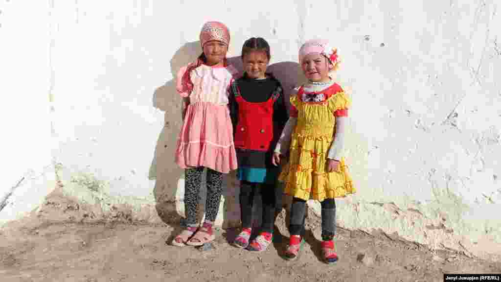 Girls pose by a wall.