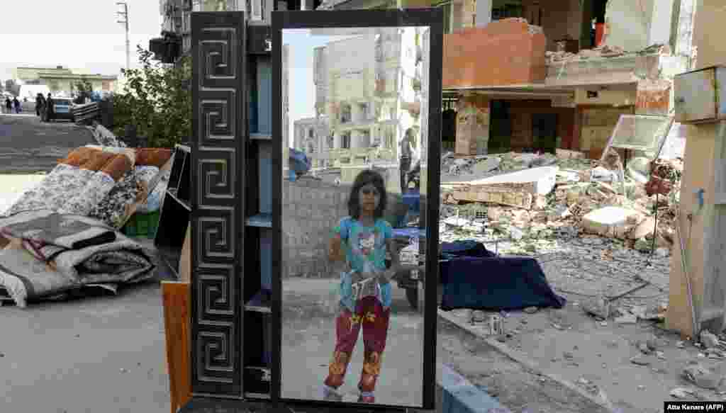 An Iranian girl looks through a salvaged mirror from a building damaged in the November 12 earthquake in the town of Sarpol-e Zahab in the western Kermanshah Province near the border with Iraq. (AFP/Atta Kenare)