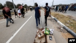 Palestinci nose pakete pomoći koju dijeli Humanitarna fondacija za Gazu, centralno područje Pojasa Gaze, 8. juna 2025.