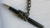 A pen wrapped in an iron chain lies on an empty notebook. Concept- restriction of freedom of speech.