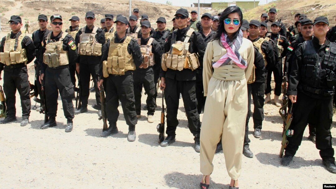 Kurdish pop star Helly Luv poses in front of Kurdish Peshmerga troops at a base in Dohuk.