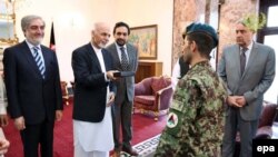 Afghan President Ashraf Ghani (2 - L) presents Afghan Army soldier, Esa Khan (C) with the keys to a new flat in recognition of his bravery in an attack by armed fighters on the Afghan Parliament in June 23.