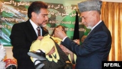 Ауғанстан президенті Хамид Карзай (оң жақта) полиомиелит вакцинасын балаға тамызып тұр. Ауғанстан, Кабул, 26 шілде 2009 жыл.