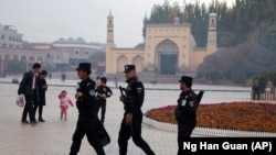 Сотрудники служб безопасности патрулируют территорию у мечети в городе Кашгаре в Синьцзяне. Ноябрь 2017 года.