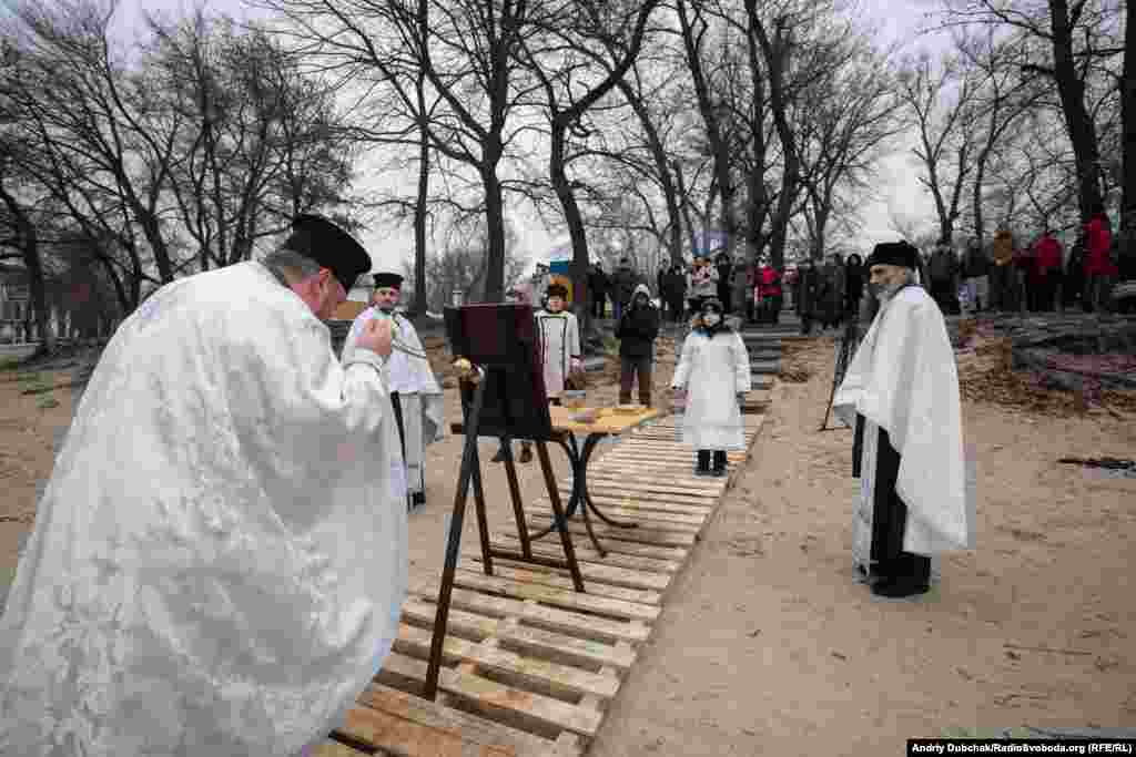 Archpriest Taras Melnyk (left) consecrates the waters of the Dnieper River.