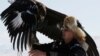 A hunter holds his tamed golden eagle during a traditional hunting contest outside the village of Kaynar in Almaty region, Kazakhstan December 8, 2019. REUTERS/Pavel Mikheyev