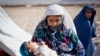 Homayra, a widow carrying her paralyzed child, lives in a makeshift refugee camp outside Mazar-e Sharif, Balkh Province. 
