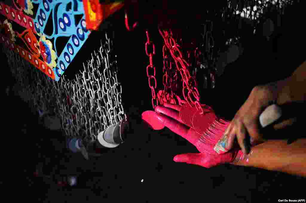 A worker takes the term "hand-painted" to a new level in Noor's workshop. Dangling chains like this are the origin of the nickname "jingle truck" for highly decorated freight vehicles. 