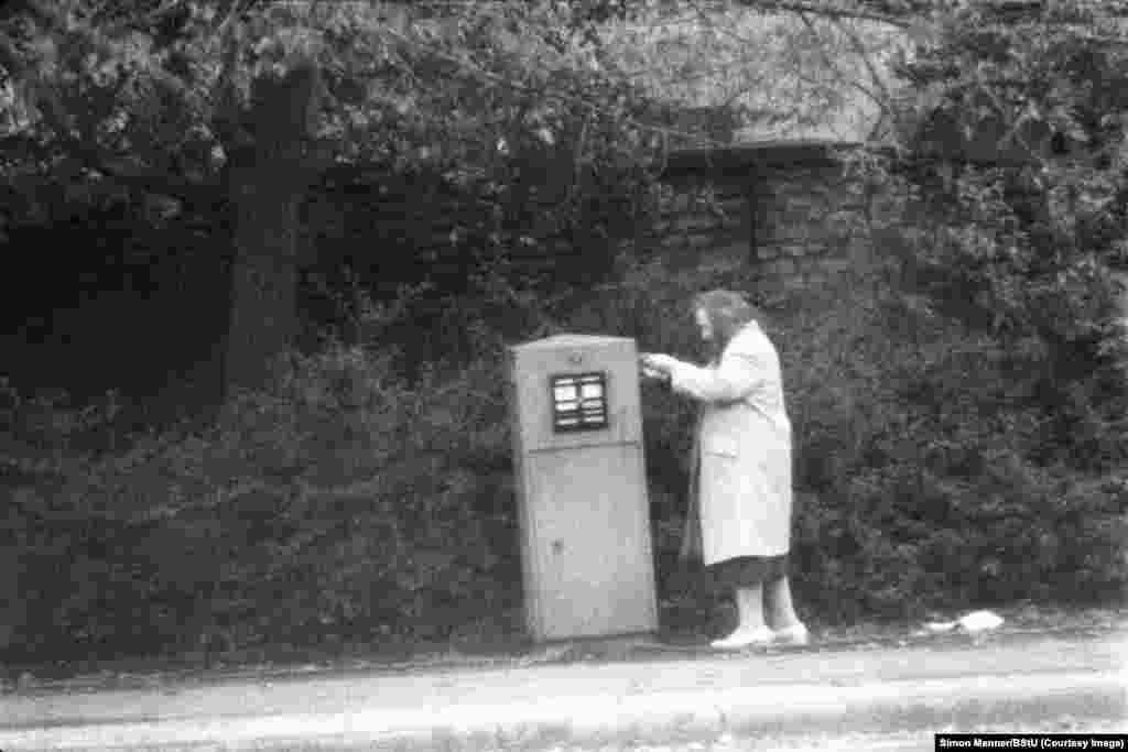 An elderly woman posting a letter on a winter day in communist East Germany (GDR).