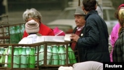 O coadă la lapte la finele anilor '90, când politicile de trecere la economia de piață deveniseră mai curajoase, dar nu ofereau ajutor celor afectați de concedieri și restructurări. Sticlele cu lapte în lăzi metalice sunt din comunism. Atunci, cozile durau ore.