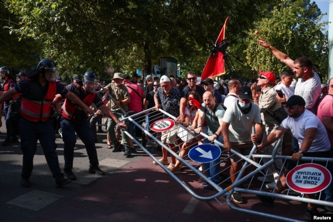 Demonstruesit mbajnë një pengesë ndërsa përleshen me policinë gjatë një demonstrate kundër qeverisë, në Tiranë, Shqipëri, 23 korrik 2026.