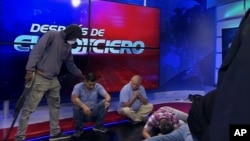Një burrë i armatosur duke qëndruar afër gazetarëve pasi disa persona të armatosur e pushtuan televizionin TC gjatë transmetimit direkt në Ekuador të martën, 9 janar 2024.