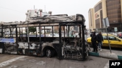 A photograph shows the wreckage of a burnt bus bearing a banner that reads "This was one of Tehran’s new buses that was paid for with the money of the people’s taxes,” in Tehran's Sadeqieh Square on January 15.