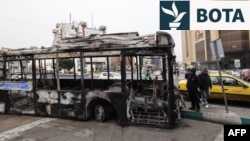 Mbetjet e një autobusi të djegur me një pankartë ku shkruhet: “Ky ishte një nga autobusët e rinj të Teheranit që u pagua me paratë e taksave të qytetarëve”, në sheshin Sadeqieh të Teheranit, më 15 janar.