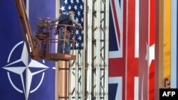 A worker installs flag on April 2 in preparation for the NATO summit in Strasbourg.