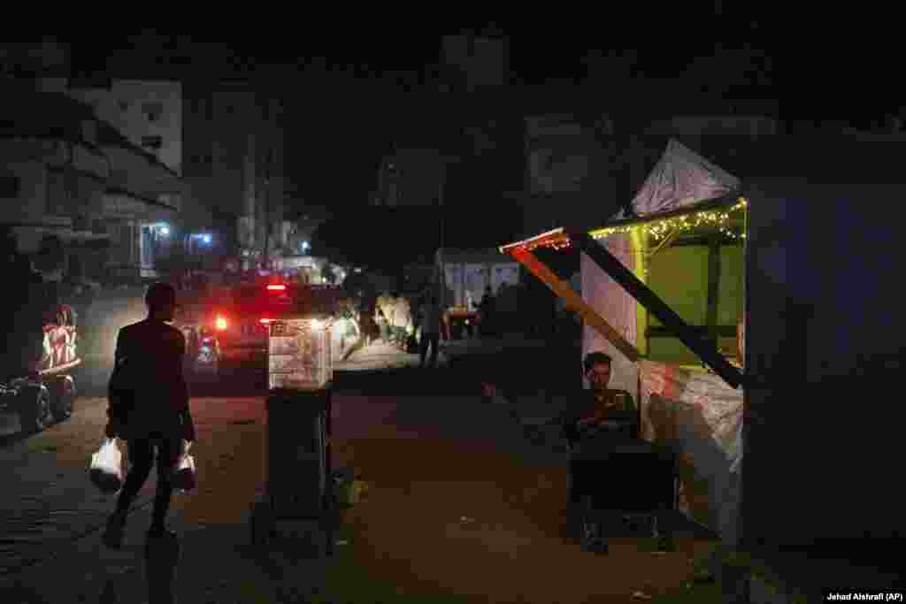 Një palestinez duke shikuar telefonin e tij teksa qëndronte pranë dyqanit të tij të improvizuar në një rrugë në Qytetin e Gazës.