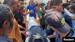 Trupul unuia dintre jurnaliștii uciși este purtat de palestinieni, la scurt timp după atacul asupra Spitalului din Nasser. 