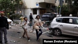 مردی با در آغوش گرفتن سگ خود در تل‌آویو در حال رفتن به پناهگاه پس از به صدا در آمدن آژیر خطر حمله هوایی است