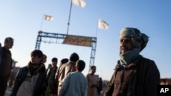 Afghan men stand near the Afghanistan-Iran border crossing of Islam Qala, on Nov. 24, 2021.