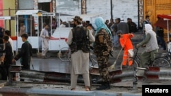 Taliban fighters stand guard at the site of the blast in Kabul on August 6. 