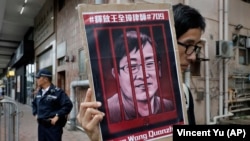 Человек с портретом известного китайского правозащитника Ван Цюаньчжана, заколоченного в Китае в тюрьму, проводит пикет у отделения связи Китая в Гонконге. 13 июля 2018 года.