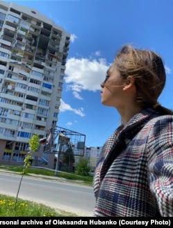 Олександра Губенко біля пошкодженої обстрілом будівлі